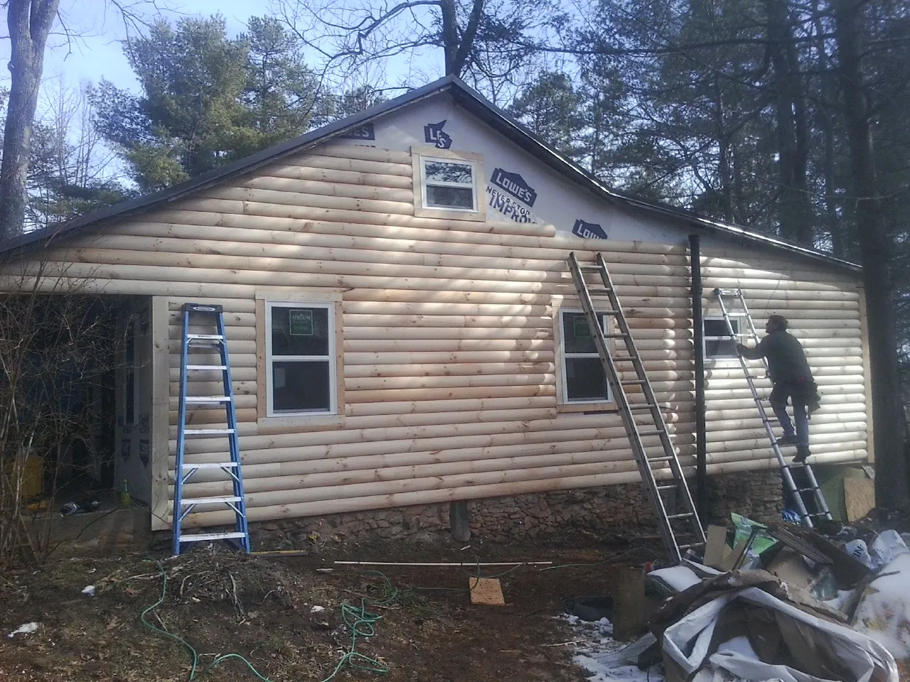 Ladders set against fresh log siding during an exterior remodel in Austin